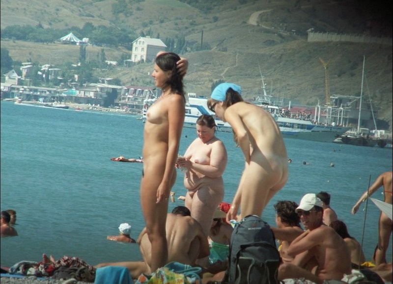 Couple of girls on busy nudist beach 