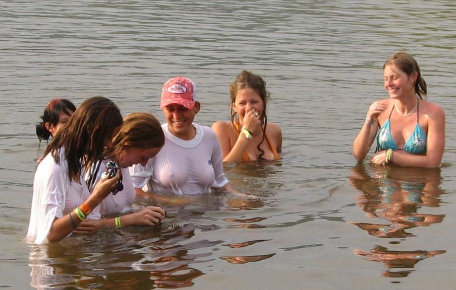 Funny girls on lake in wet shirts