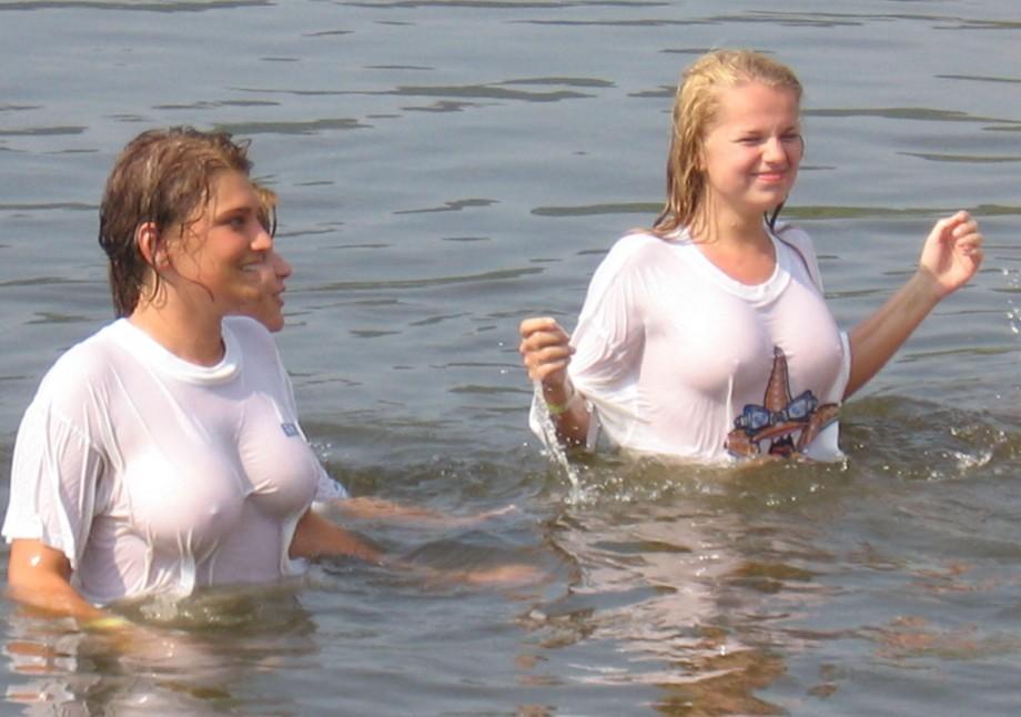 Funny girls on lake in wet shirts