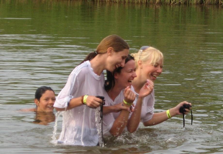 Funny girls on lake in wet shirts