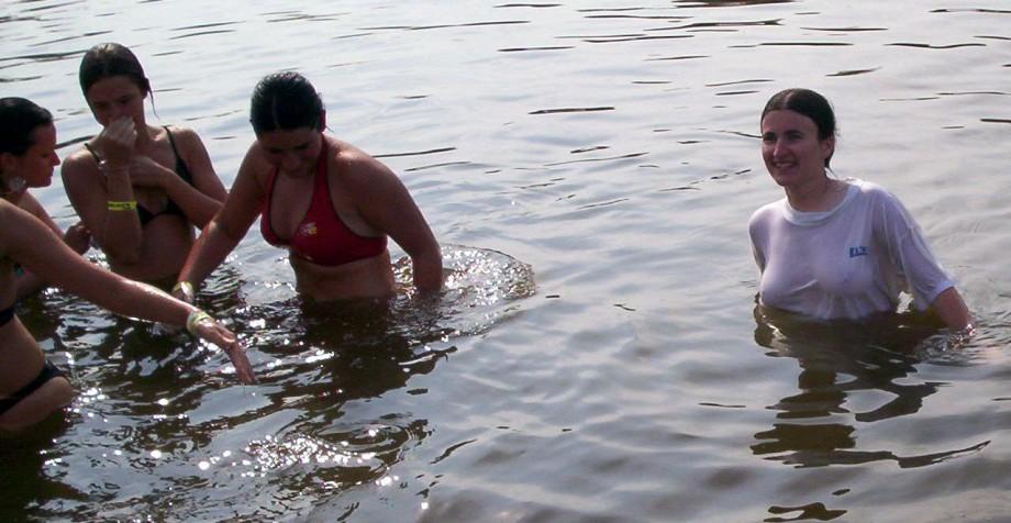 Funny girls on lake in wet shirts