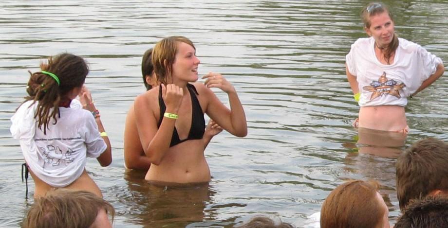 Funny girls on lake in wet shirts