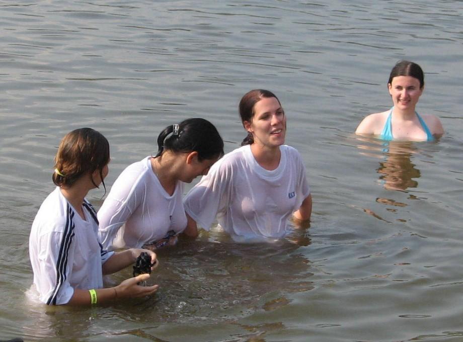 Funny girls on lake in wet shirts