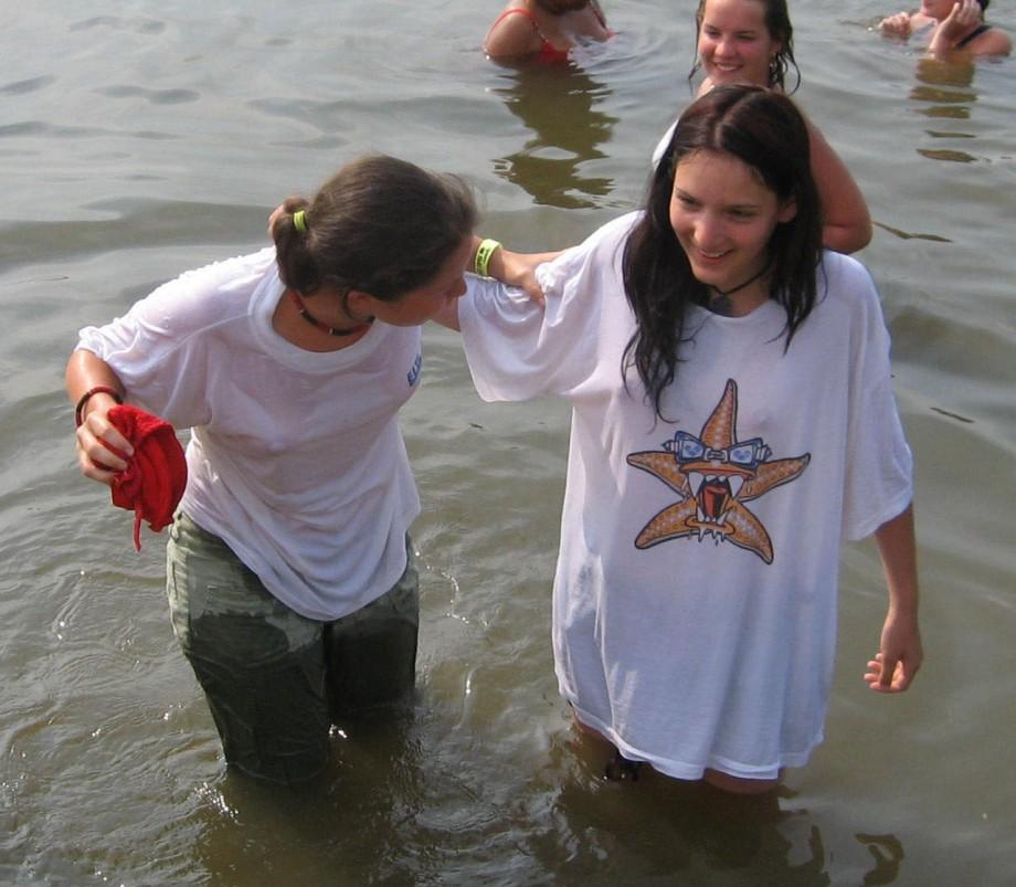 Funny girls on lake in wet shirts